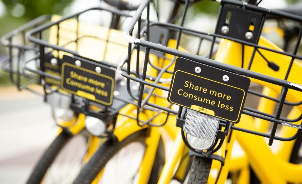Close up on the handle bar basket with 'Share More Consume Less' sign