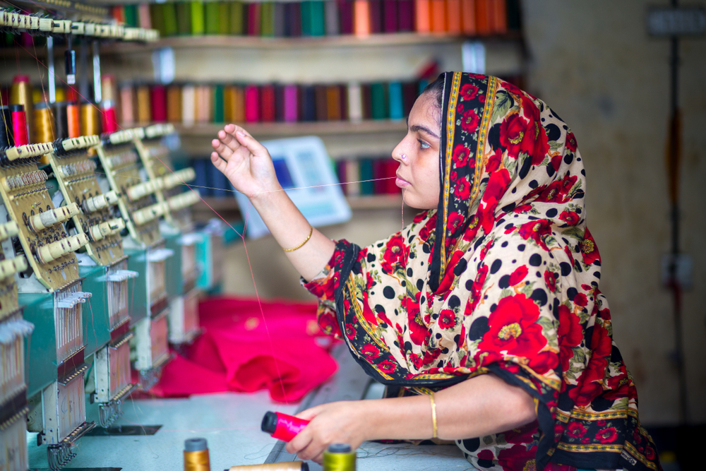 Garment worker working with computerized embroidery machine in Madhabdi