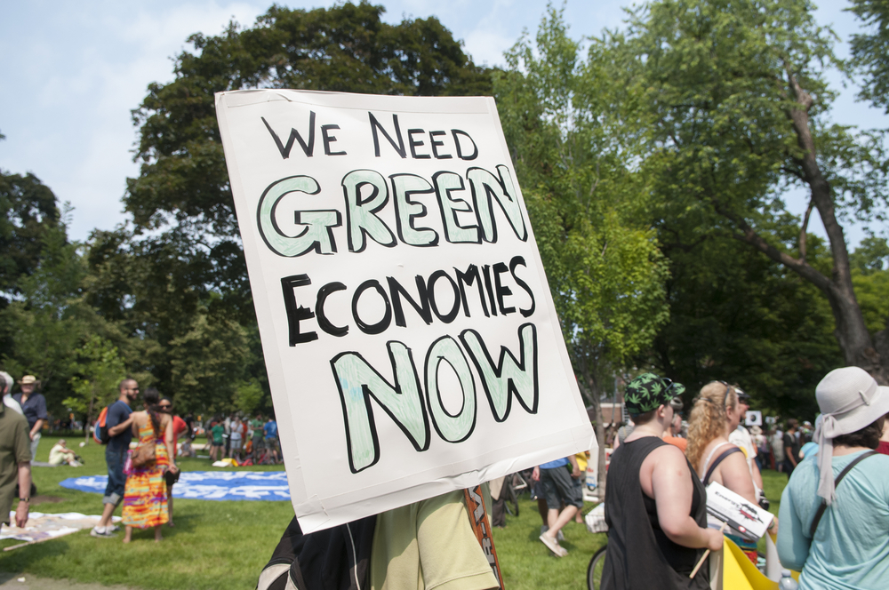 Person holds sign that reads "We need green economies now"