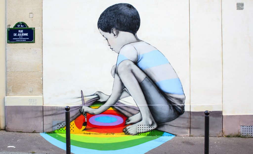 Graffiti in Paris of a child painting a rainbow