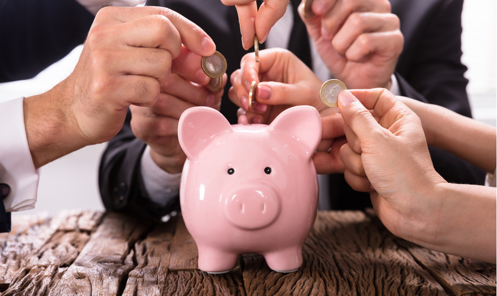 Hands inserting coins into a piggy bank