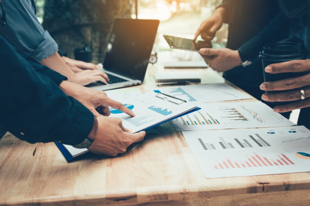 Teamwork with business people analyzing data on a desk in a meeting room. Image courtesy of Shutterstock.