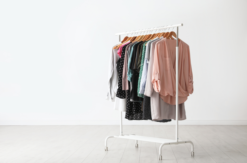 Wardrobe rack with clothes hanging near white wall indoors