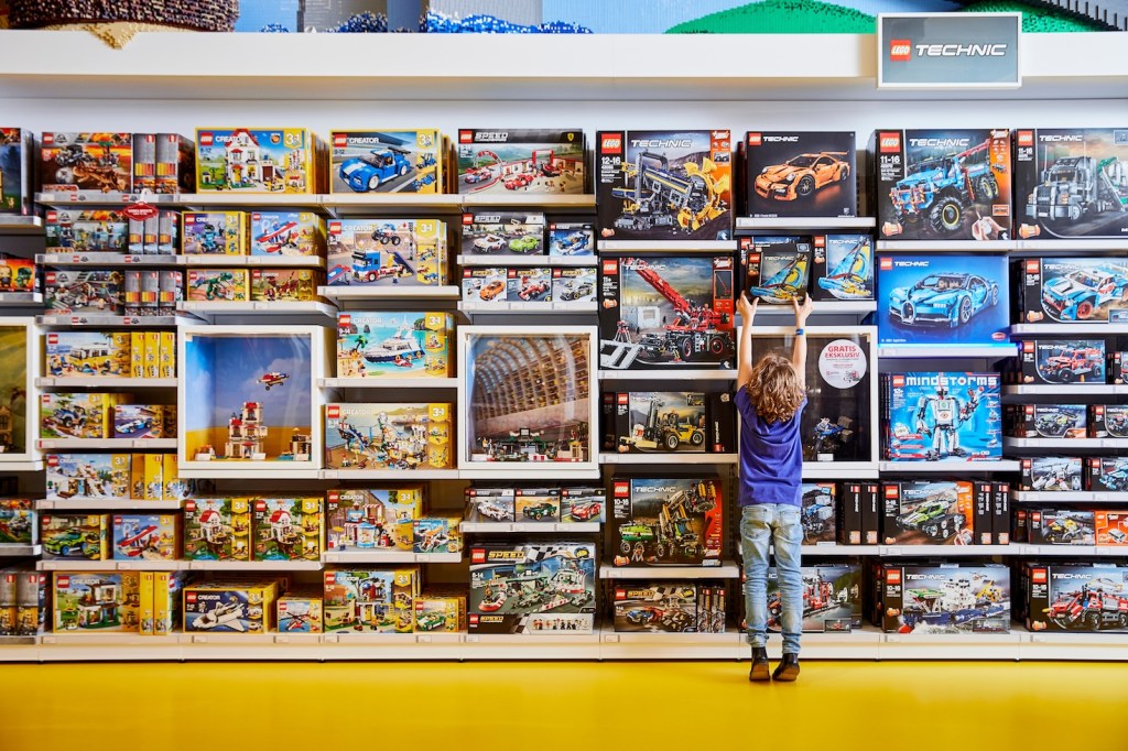 Child reaching for a Lego box in a toy retailer.