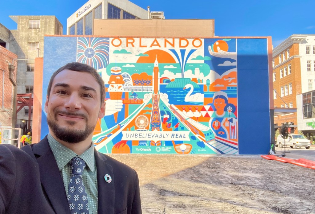 A self-taken photo of Chris Castro in front of a mural in Orlando.