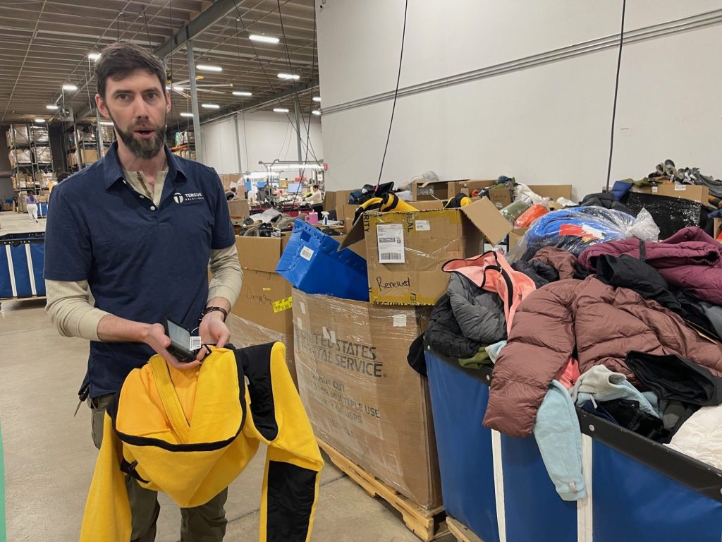 Luke Fowler, director of repairs and upcycling, shows how Tersus Solutions has labeled a yellow Dinali jacket from The North Face to track its way through cleaning and distribution.