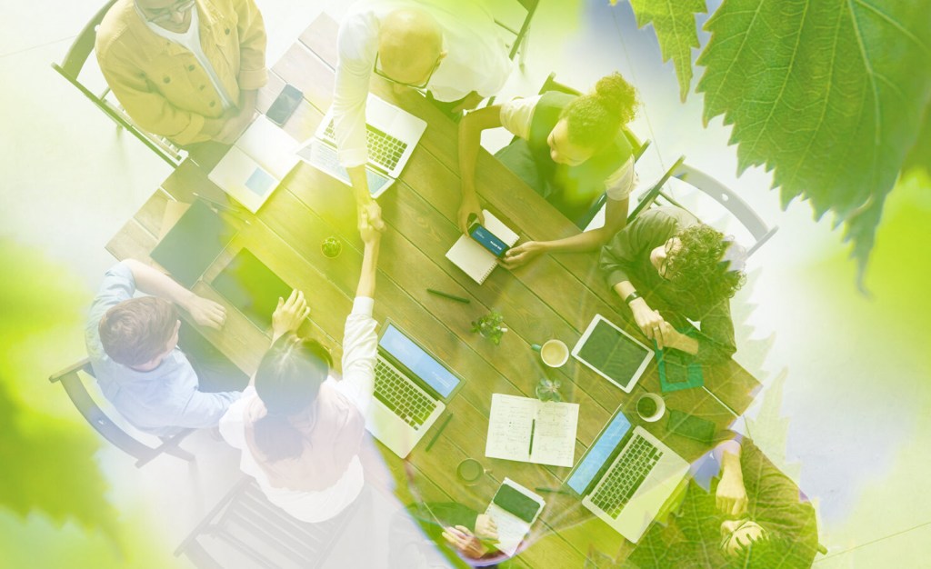 People at a table working with a green tinge on top.