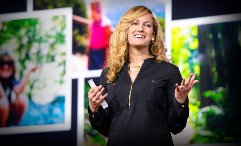 Blonde woman speaking in front of bright photographs