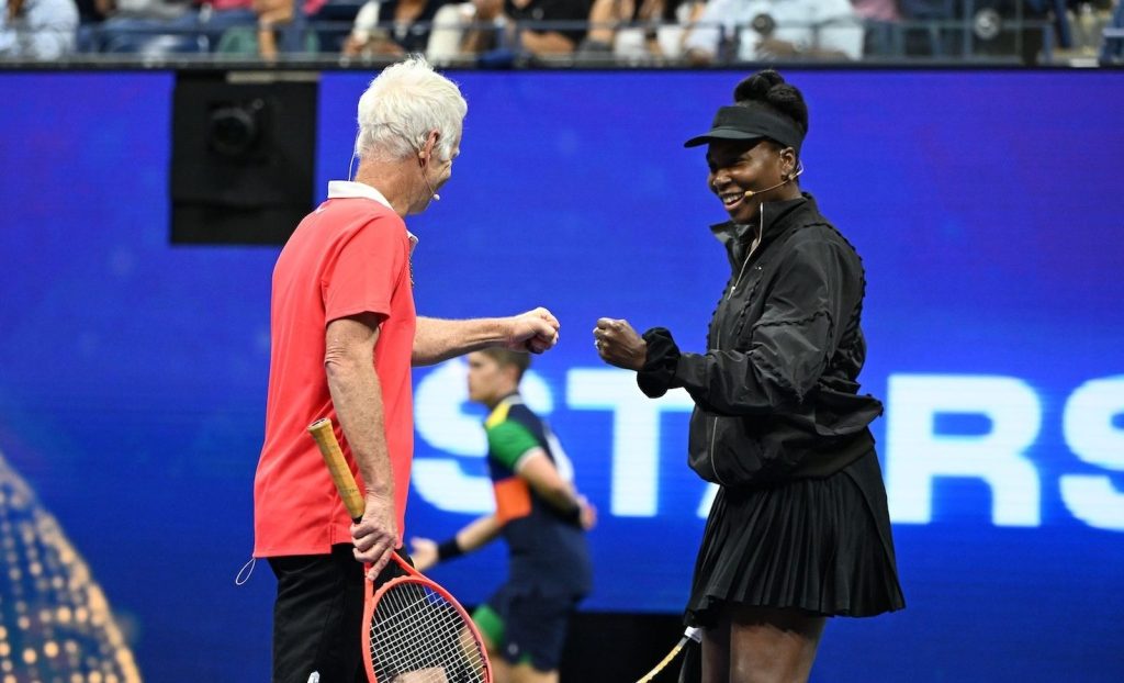 Venus Williams, in a wool outfit by Luar, greets John McEnroe at the US Open in August 2025.