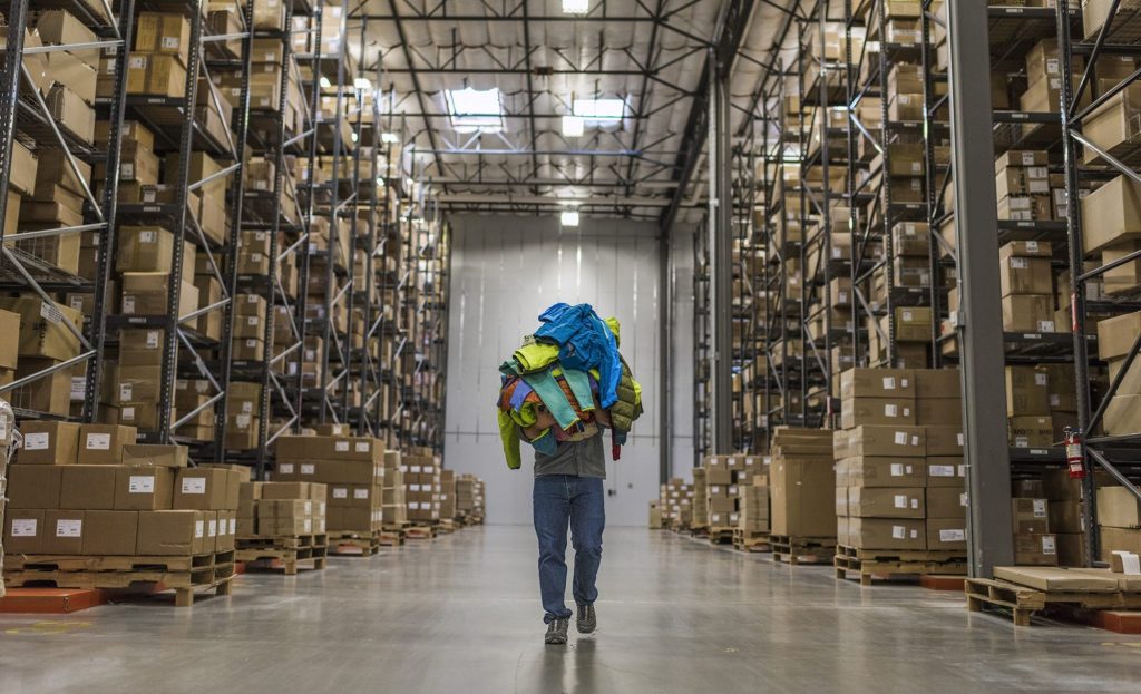 Warehouse with boxes and person carrying garments