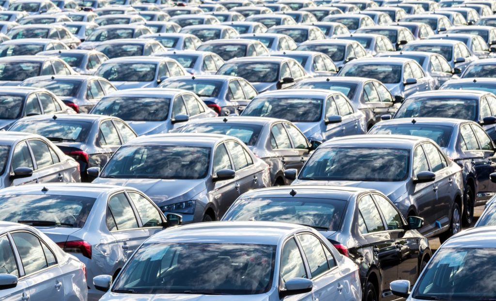 Rows of a new cars parked in a distribution center on a car factory on a sunny day.