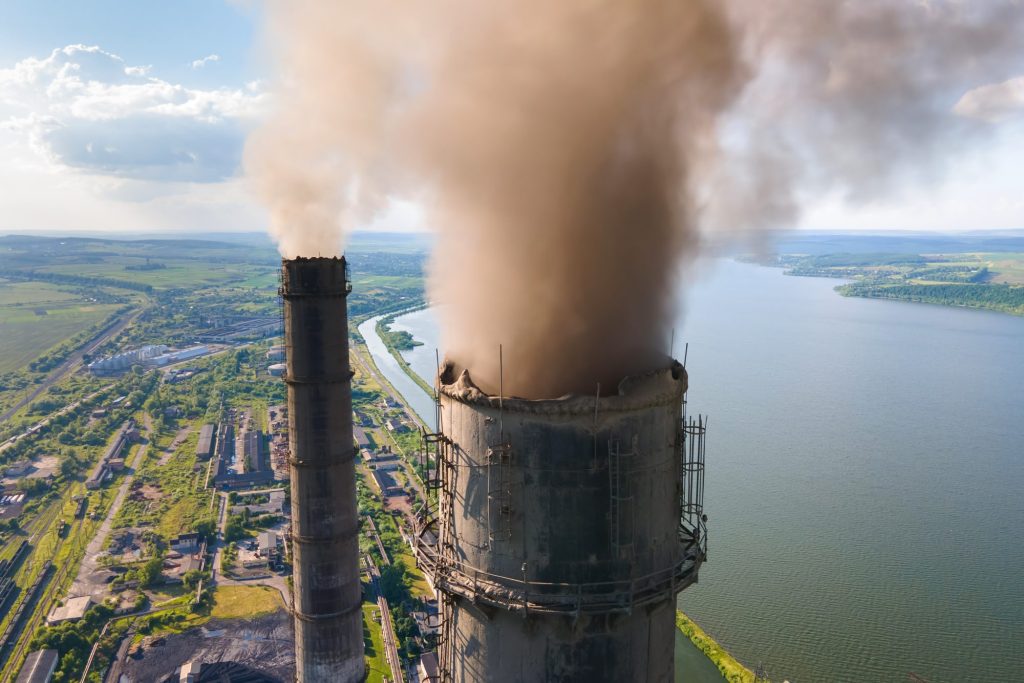 Aerial view of coal power plant high pipes with black smokestack polluting atmosphere.