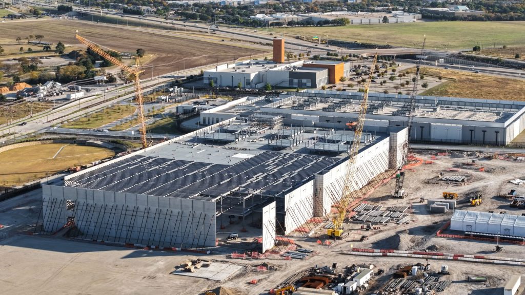 Aerial view of a large data center building and an industrial zone in development